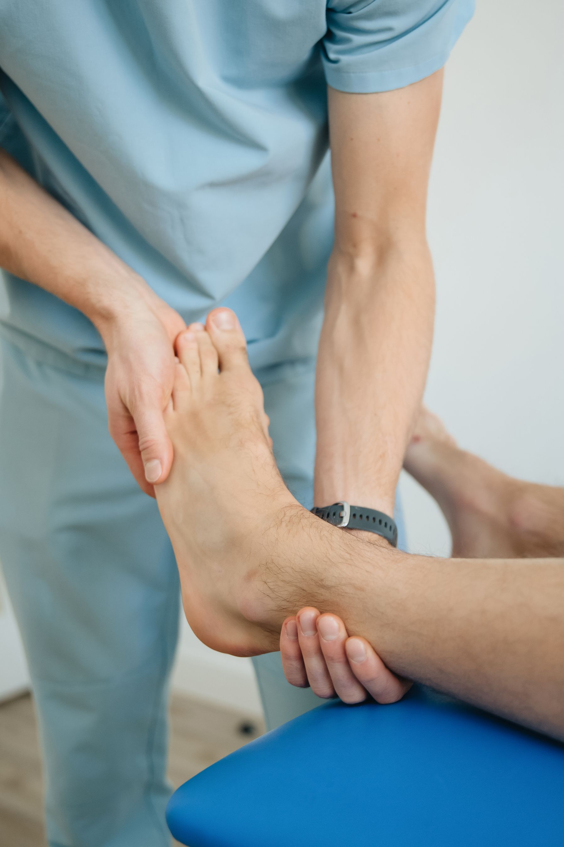 Physiotherapist supporting a patient’s foot and ankle during hands-on treatment.