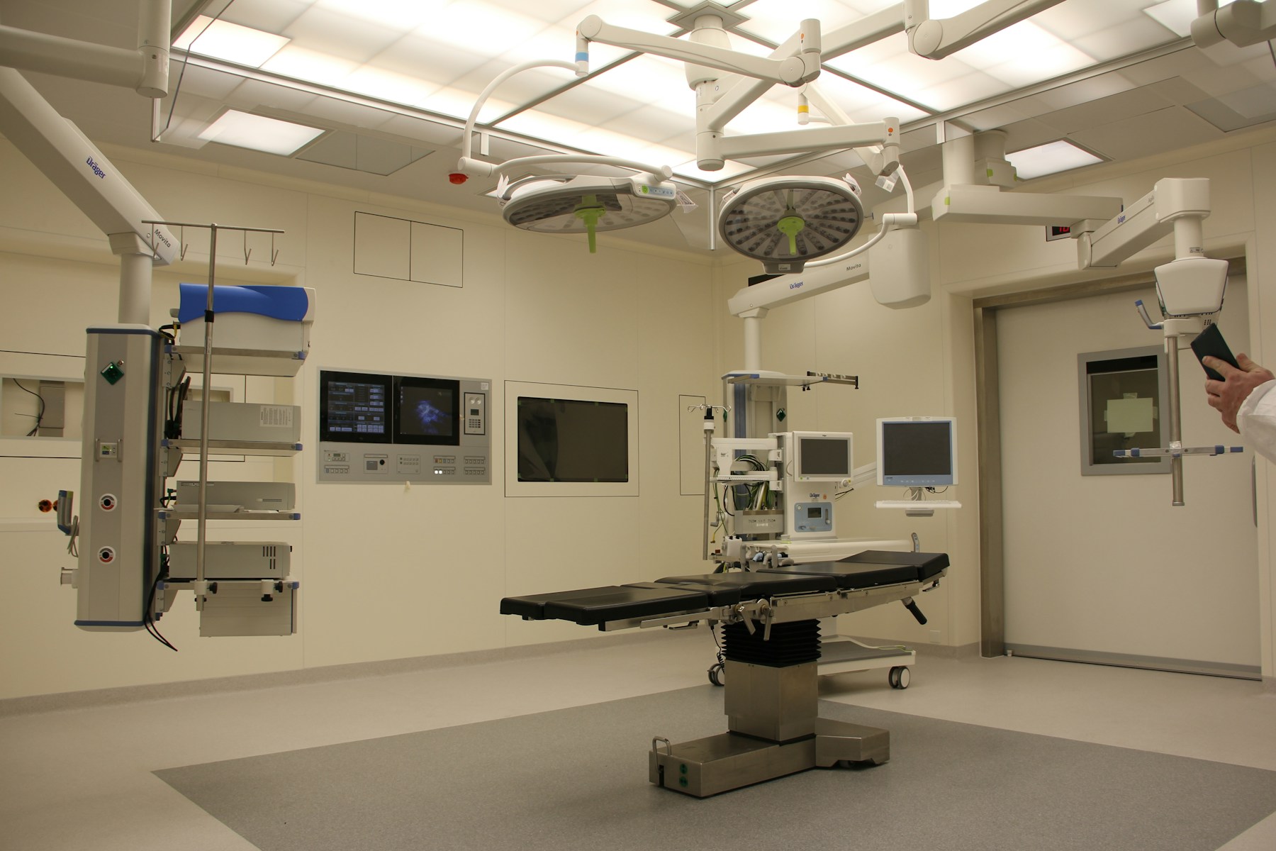 Illustrative operating theatre with a surgical table, overhead lights and medical monitors.